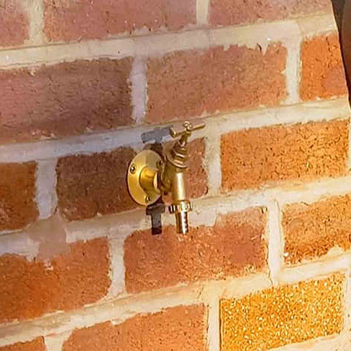 image of an brass tap fitted outside on a red brick wall